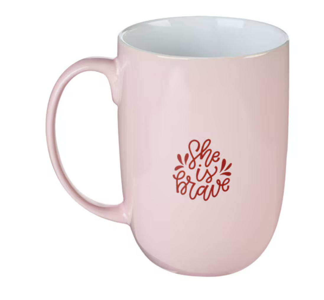 Pink ceramic coffee mug with "She is Brave" gold foil text, Christian Art Gifts drinkware, perfect for inspiring mornings.