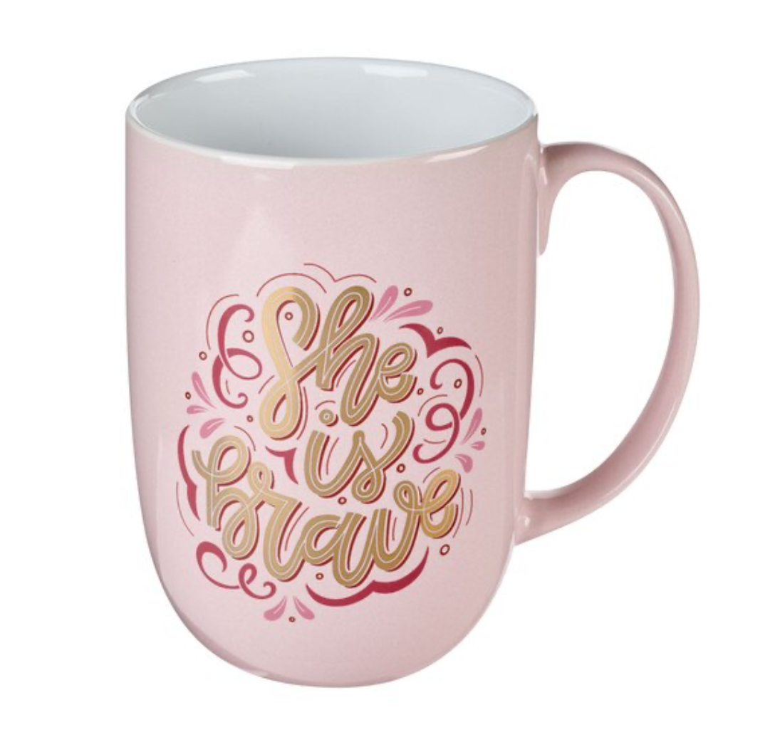 Pink ceramic coffee mug with gold foil lettering "She is Brave" by Christian Art Gifts, featuring a stylish and inspiring design.